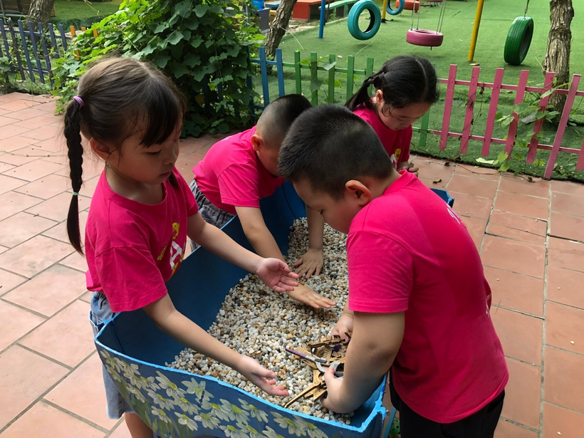 A group of children playing with rocks

Description automatically generated
