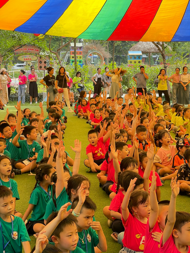 A group of children sitting on the ground with their hands up

Description automatically generated