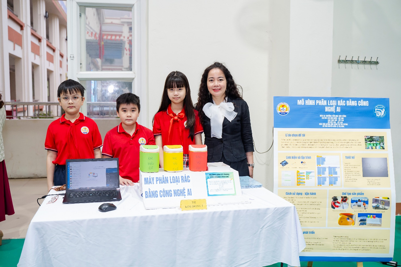 A group of children standing next to a table with a computerDescription automatically generated