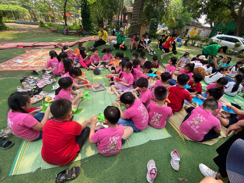 A group of children sitting on a blanket in a park

Description automatically generated