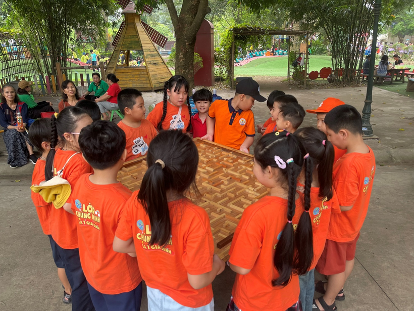 A group of kids in orange shirts holding a wooden board

Description automatically generated